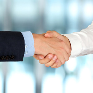 Close-up image of a firm handshake between two colleagues in the office.